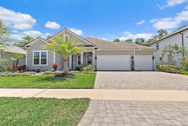 view of front of house featuring a front yard, decorative driveway, and a garage