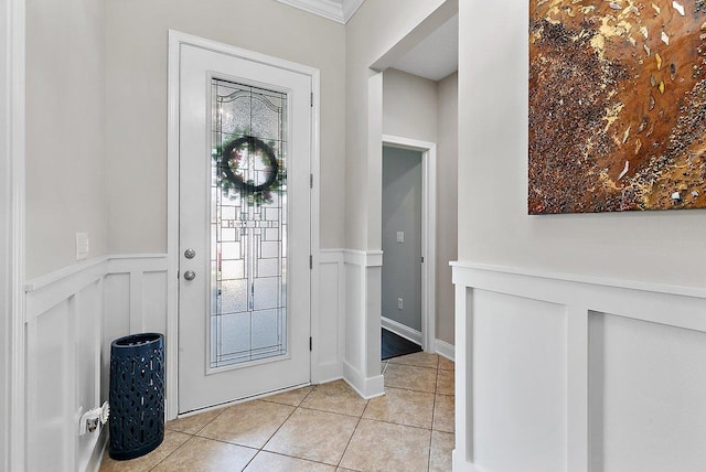 foyer entrance with light tile patterned floors, a wainscoted wall, and a decorative wall