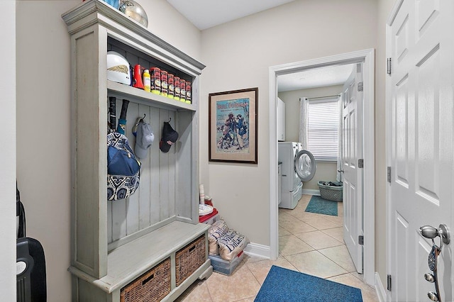 mudroom with light tile patterned floors, baseboards, and washing machine and clothes dryer