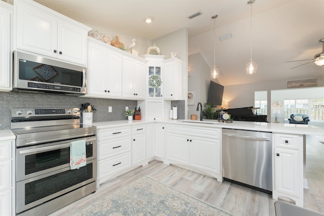 kitchen featuring stainless steel appliances, a peninsula, a sink, visible vents, and light countertops