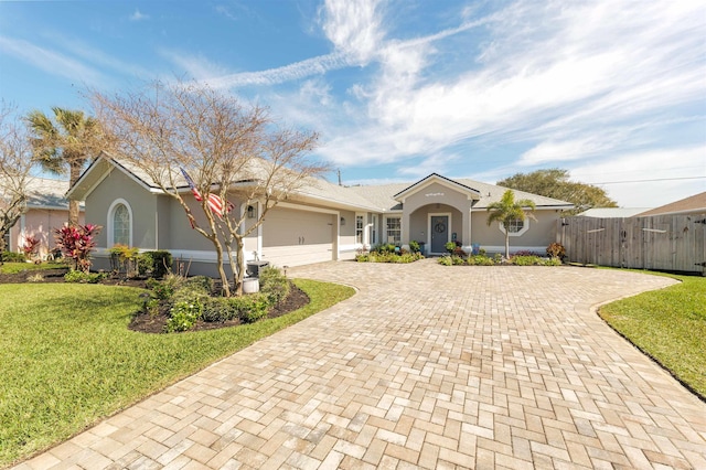 ranch-style home featuring an attached garage, a front lawn, decorative driveway, and stucco siding