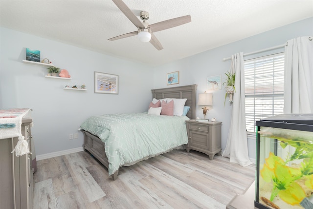 bedroom with a textured ceiling, ceiling fan, light wood-type flooring, and baseboards