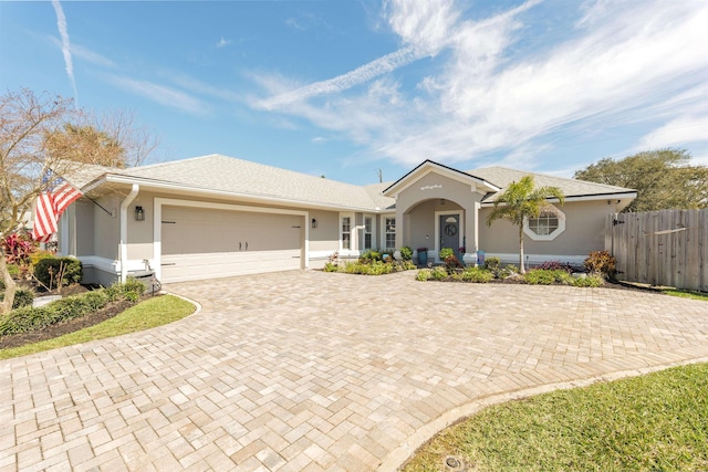 ranch-style home with a garage, decorative driveway, fence, and stucco siding