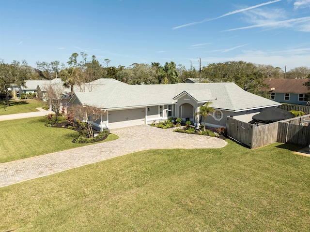 ranch-style home featuring a front yard, decorative driveway, fence, and an attached garage