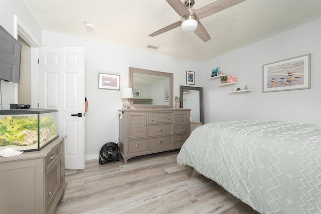 bedroom featuring a ceiling fan, light wood-type flooring, visible vents, and a textured ceiling