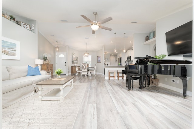 living room featuring visible vents, light wood-style flooring, a ceiling fan, vaulted ceiling, and baseboards