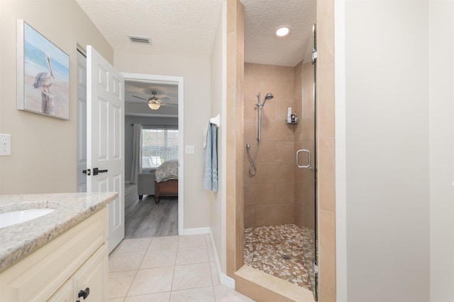 ensuite bathroom featuring connected bathroom, a shower stall, a textured ceiling, vanity, and tile patterned flooring