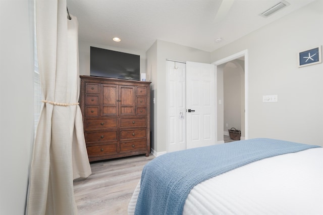 bedroom featuring baseboards, visible vents, arched walkways, light wood-type flooring, and recessed lighting