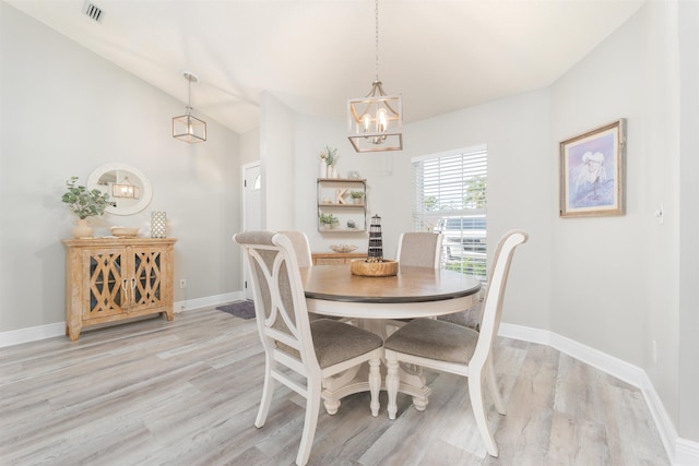 dining area featuring light wood-style flooring, visible vents, baseboards, vaulted ceiling, and an inviting chandelier