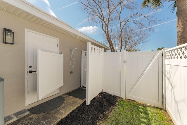 exterior space featuring a gate, fence, and stucco siding