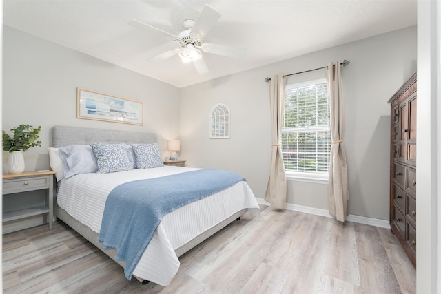 bedroom with light wood-style flooring, baseboards, and a ceiling fan