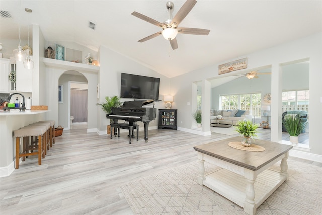 living area with light wood-type flooring, baseboards, visible vents, and arched walkways