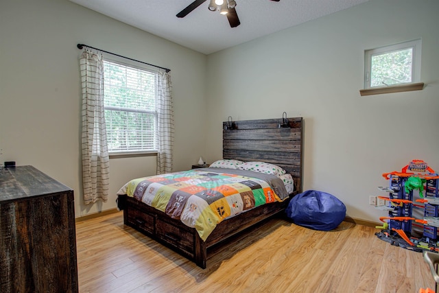 bedroom with ceiling fan, a textured ceiling, baseboards, and wood finished floors