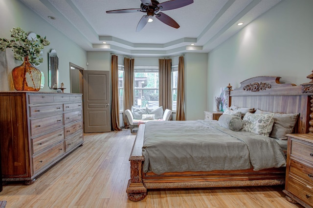 bedroom with light wood-type flooring, ceiling fan, a raised ceiling, and recessed lighting