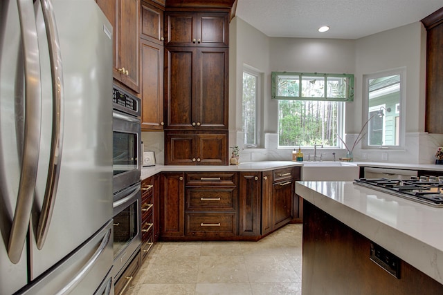 kitchen featuring a textured ceiling, recessed lighting, stainless steel appliances, a sink, and light countertops