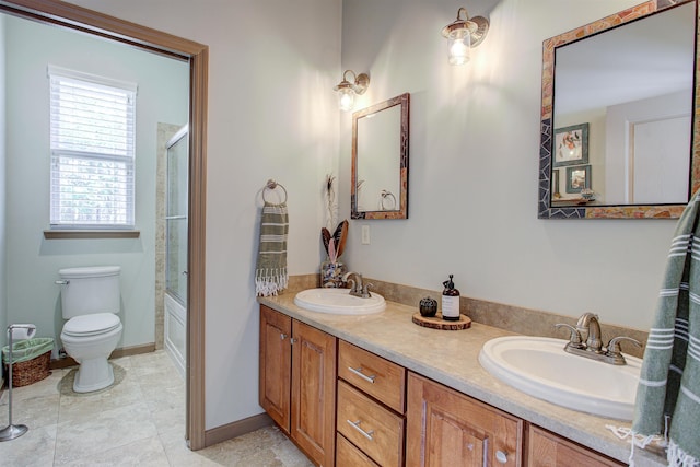 full bath featuring double vanity, a sink, toilet, and an enclosed shower