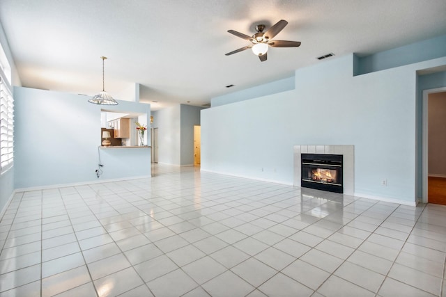 unfurnished living room with a fireplace, light tile patterned floors, and ceiling fan