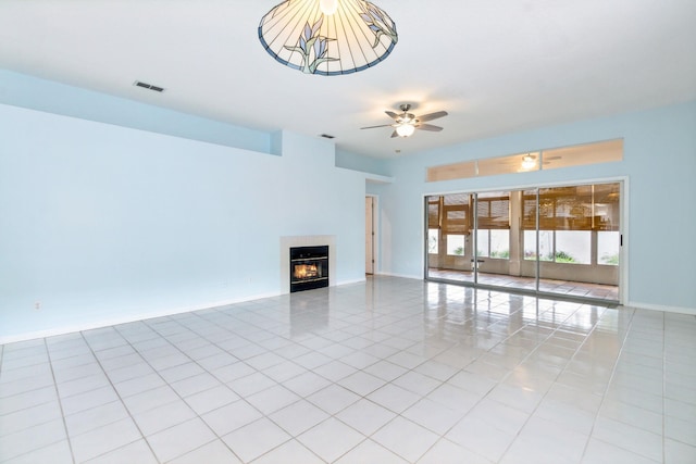 unfurnished living room with ceiling fan, light tile patterned floors, and a tiled fireplace