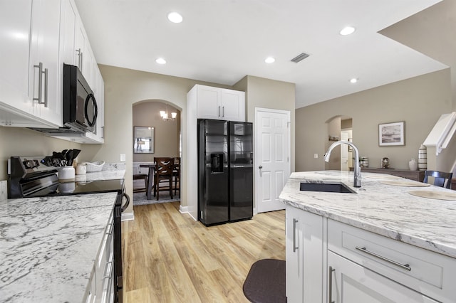 1125 S Marsh Wind Way, Ponte Vedra Beach, FL 32082 - kitchen with a sink, arched walkways, white cabinetry, light wood-type flooring, and black appliances