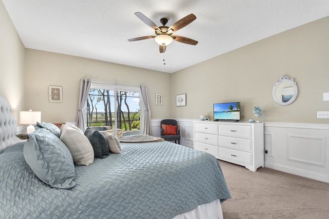 1125 S Marsh Wind Way, Ponte Vedra Beach, FL 32082 - bedroom with ceiling fan, a textured ceiling, access to exterior, a wainscoted wall, and light carpet