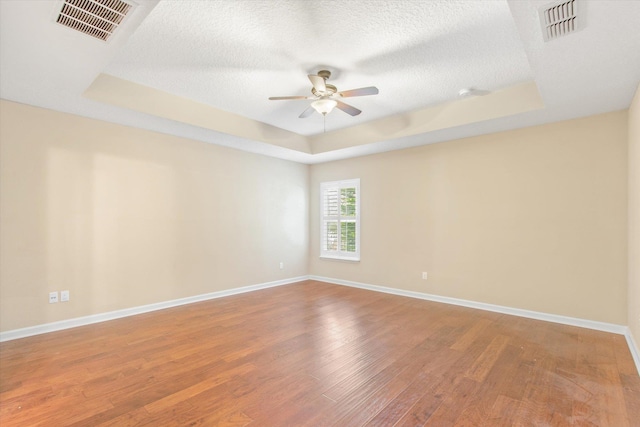 unfurnished room featuring a tray ceiling, wood-type flooring, a textured ceiling, and ceiling fan