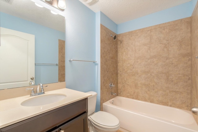 full bathroom with tiled shower / bath, vanity, toilet, and a textured ceiling