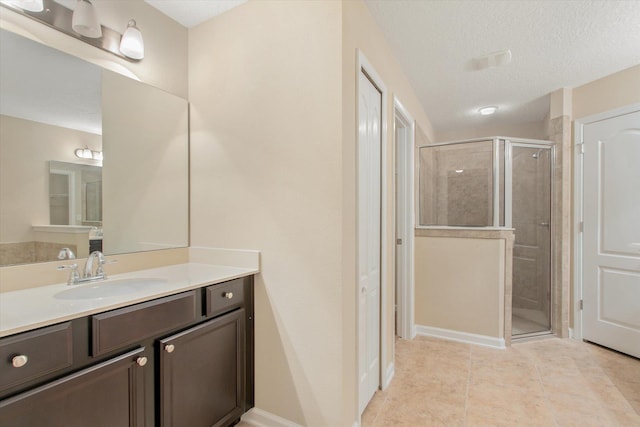 bathroom with tile patterned flooring, vanity, a textured ceiling, and a shower with shower door