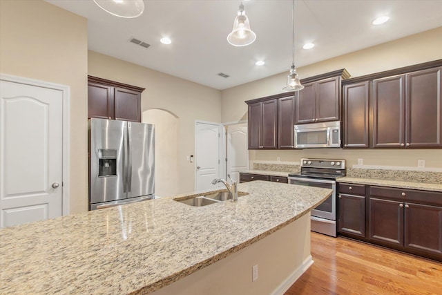 kitchen with sink, decorative light fixtures, light stone countertops, and appliances with stainless steel finishes