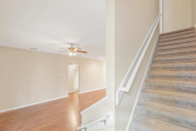 staircase featuring ceiling fan and wood-type flooring