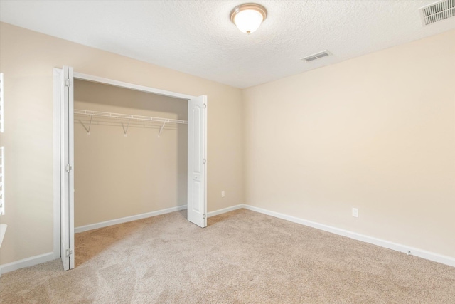 unfurnished bedroom with light carpet, a closet, and a textured ceiling