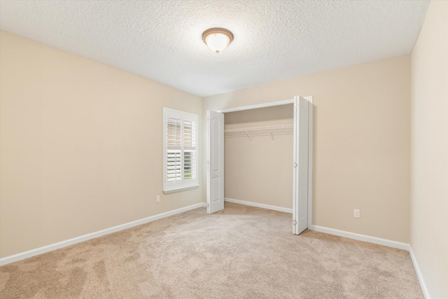 unfurnished bedroom with light carpet, a textured ceiling, and a closet