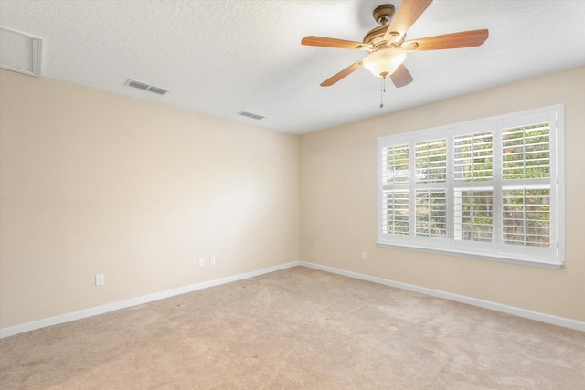 spare room featuring ceiling fan, light colored carpet, and a textured ceiling