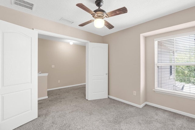 carpeted spare room with ceiling fan and a textured ceiling