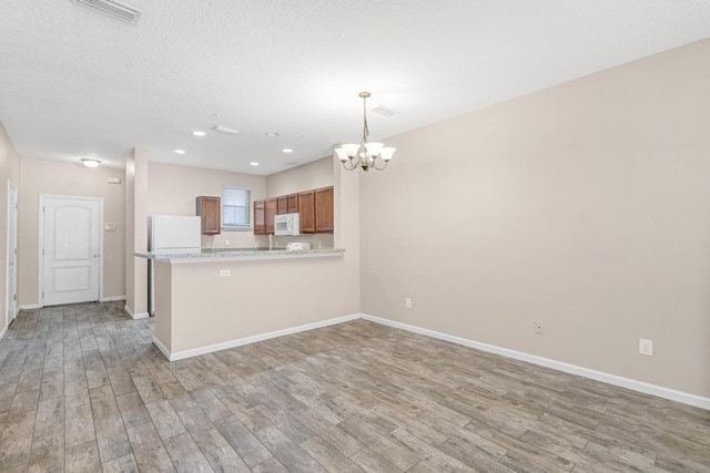 kitchen featuring kitchen peninsula, decorative light fixtures, light hardwood / wood-style floors, and white appliances