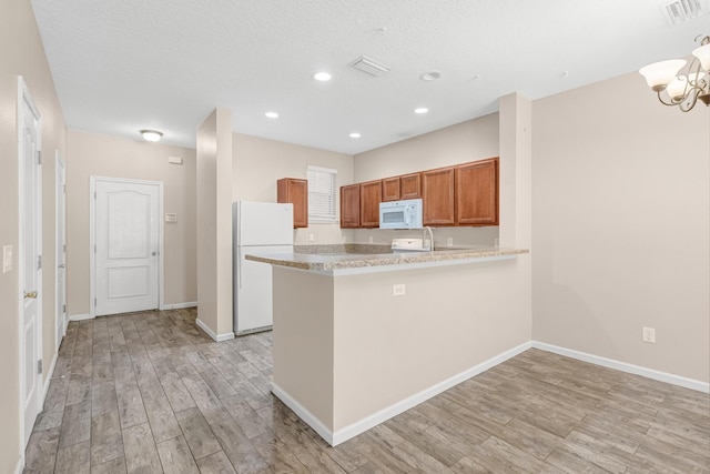 kitchen with kitchen peninsula, white appliances, and light hardwood / wood-style floors