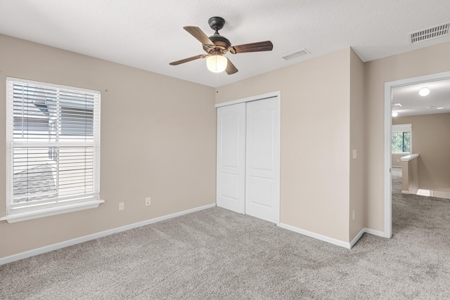 unfurnished bedroom with ceiling fan, light colored carpet, and a closet