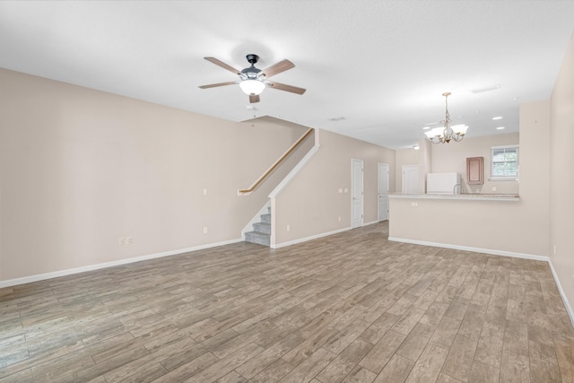 unfurnished living room with ceiling fan with notable chandelier and light hardwood / wood-style flooring