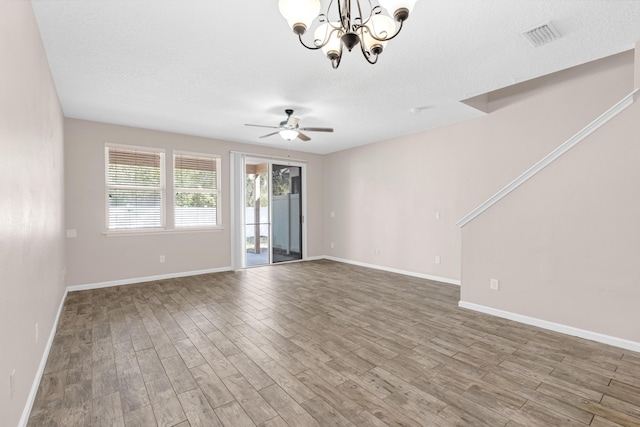 spare room with a textured ceiling, ceiling fan with notable chandelier, and hardwood / wood-style flooring