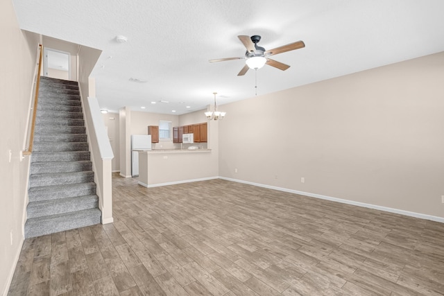 unfurnished living room with a textured ceiling, light hardwood / wood-style floors, and ceiling fan with notable chandelier