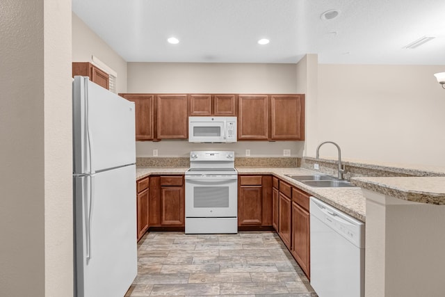 kitchen featuring kitchen peninsula, light wood-type flooring, light stone counters, white appliances, and sink