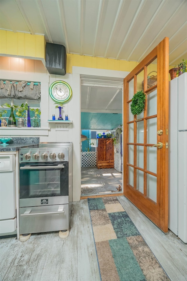 kitchen featuring stainless steel electric stove, wood-type flooring, and white refrigerator