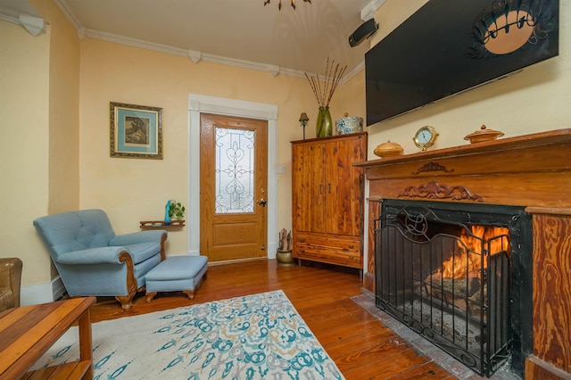 sitting room with ornamental molding and dark wood-type flooring