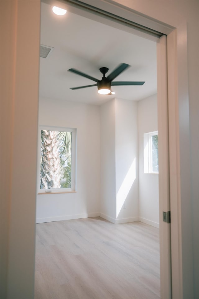 unfurnished room featuring light wood-style floors, a wealth of natural light, baseboards, and ceiling fan
