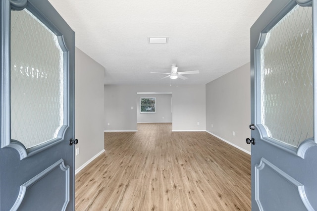 empty room with ceiling fan, a textured ceiling, and light wood-type flooring