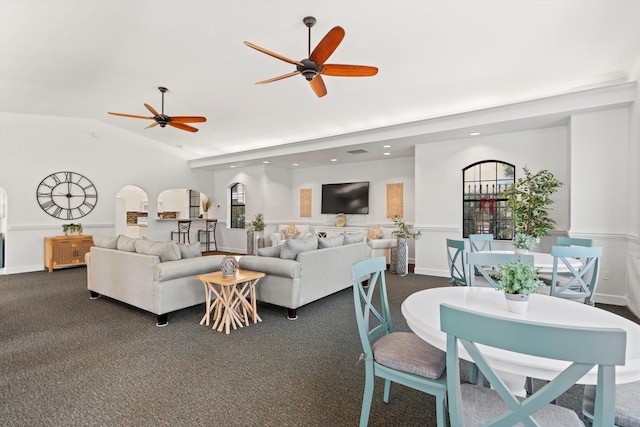 living room with ceiling fan, lofted ceiling, and dark colored carpet