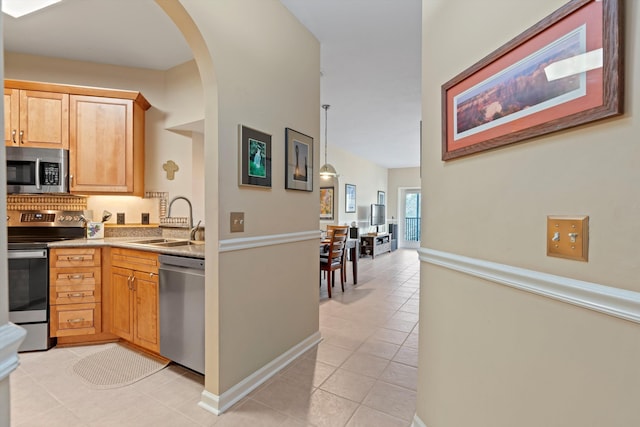 kitchen with pendant lighting, appliances with stainless steel finishes, sink, and light tile patterned floors