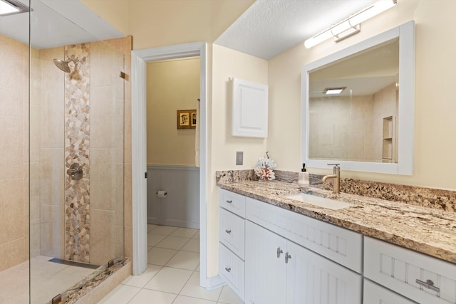 bathroom featuring a tile shower, vanity, and tile patterned floors