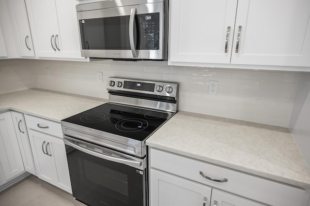 kitchen with stainless steel appliances, decorative backsplash, and white cabinets