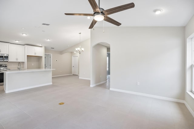 unfurnished living room featuring sink, ceiling fan with notable chandelier, and vaulted ceiling