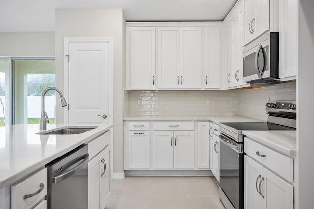 kitchen with appliances with stainless steel finishes, sink, white cabinets, and decorative backsplash